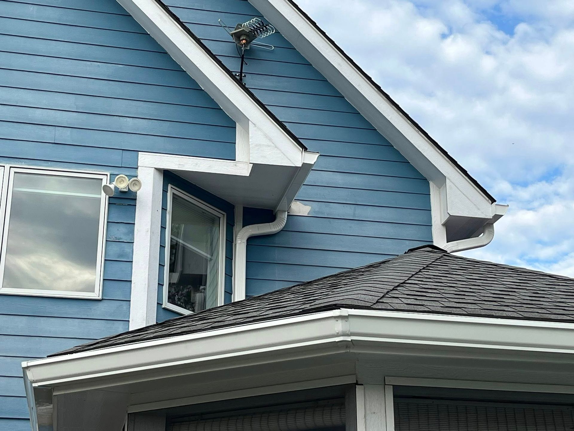 New white gutters installed on blue multi story house