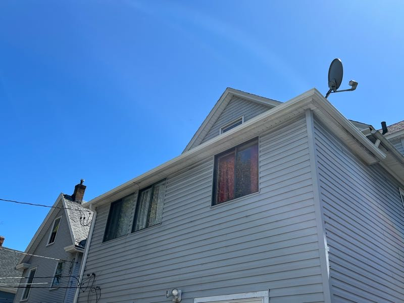 A new gutter system installed on a light blue house seen from below