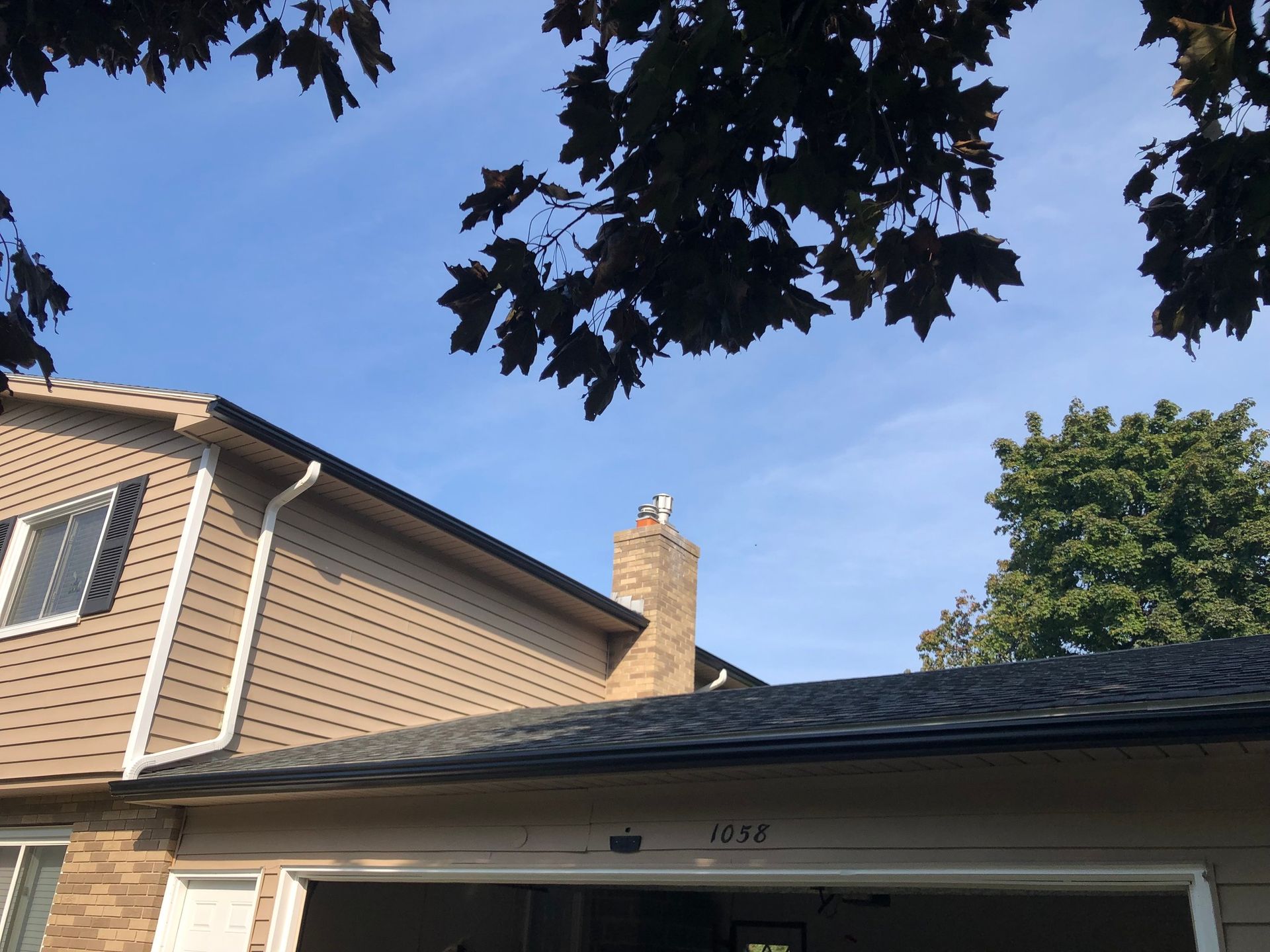 A white two-tier gutter system installed on a brown house