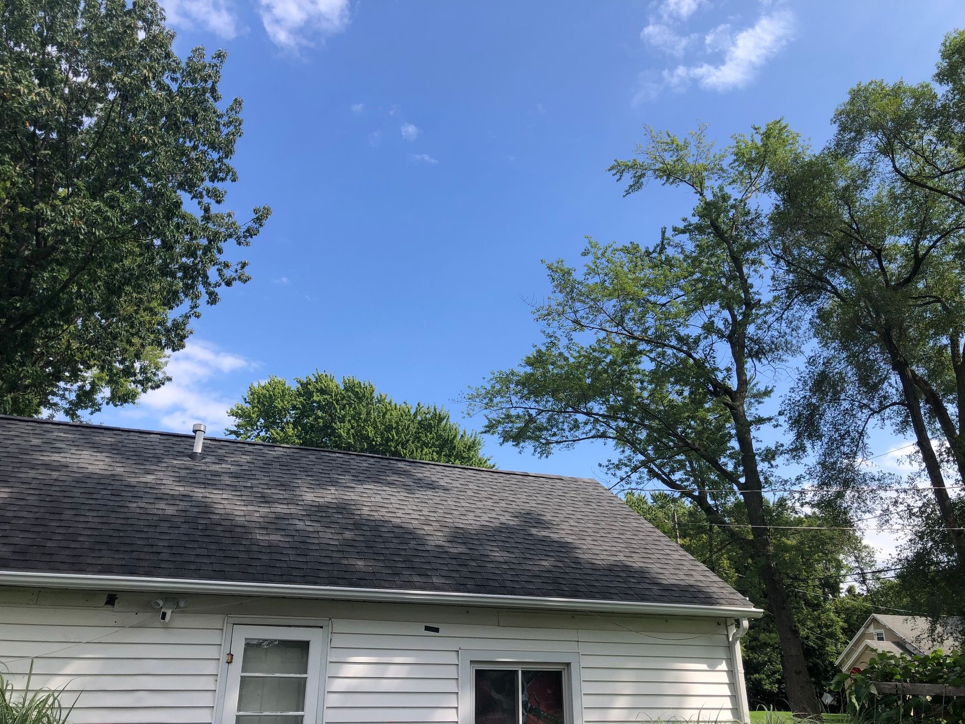 New gutters and downspout installed on a light colored house seen from a distance
