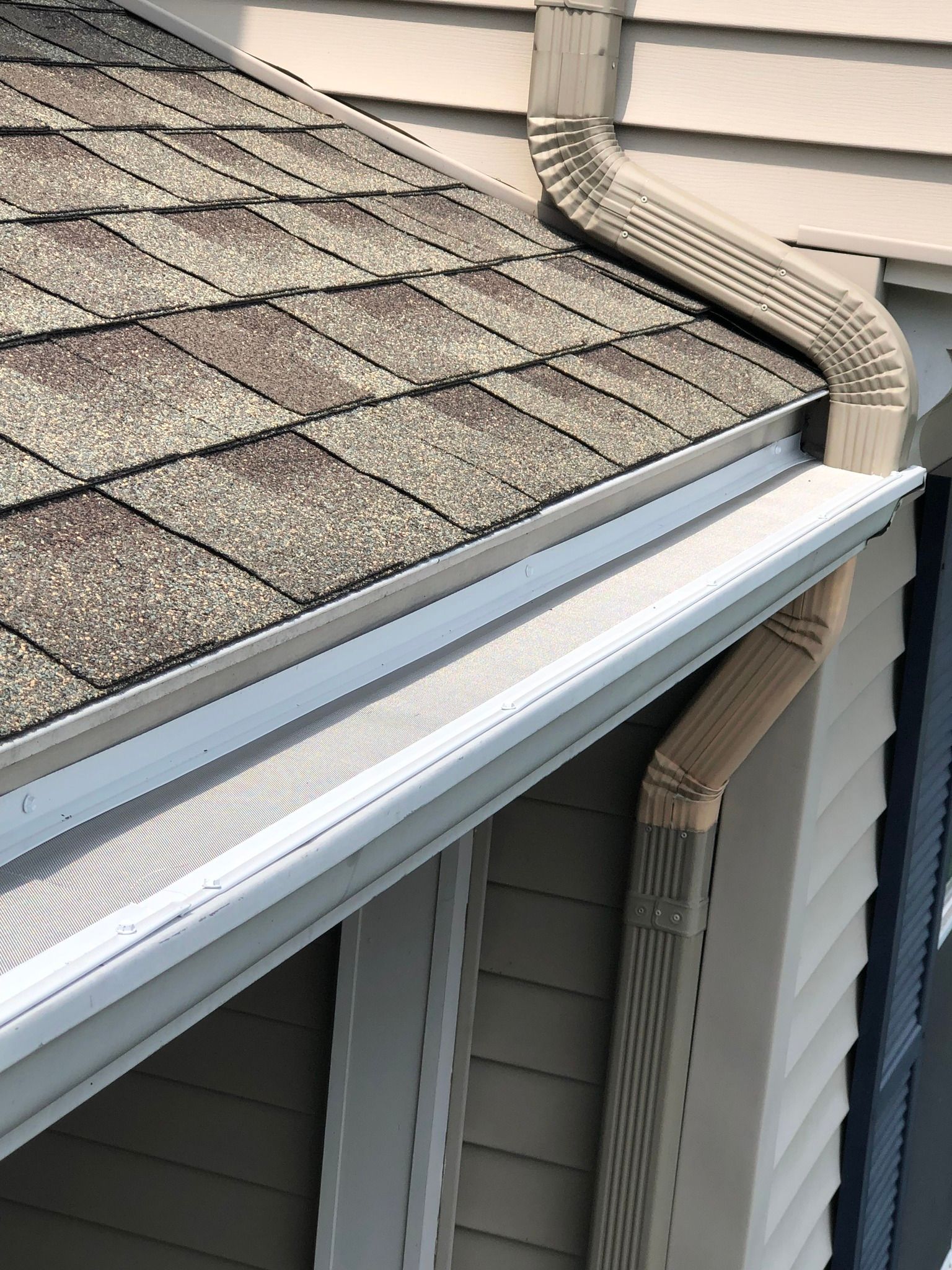 A brand new gutter guard system installed on top of a white gutter system