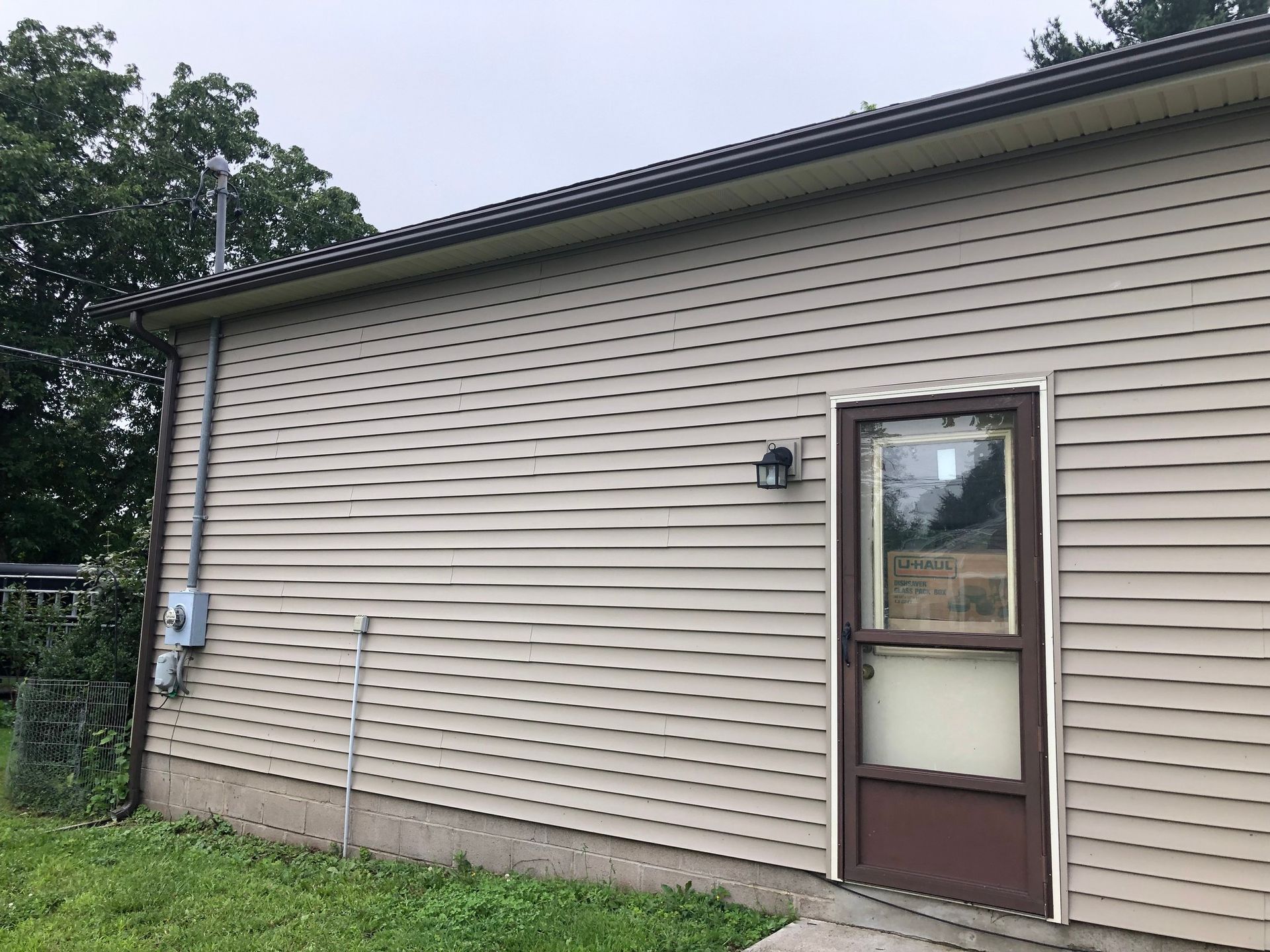 Dark-colored gutter system installed on a light brown house