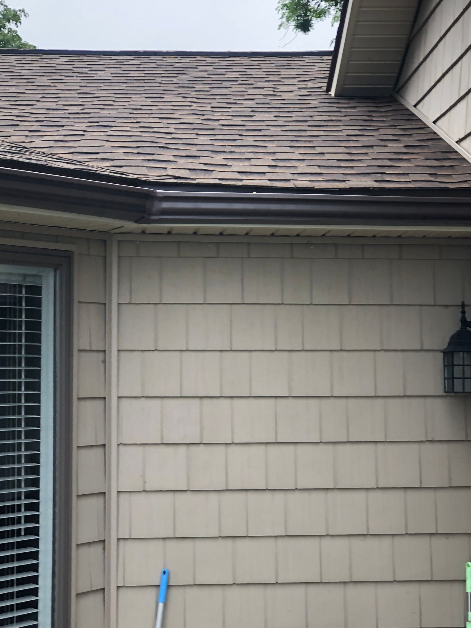 Black gutters installed on a yellow house