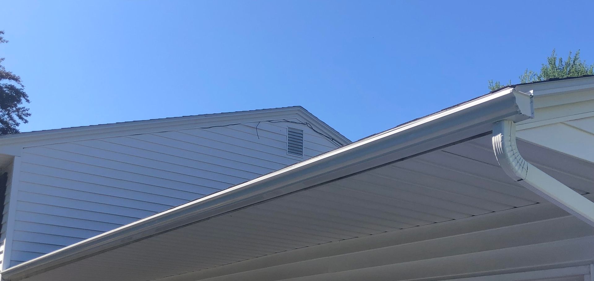 New gutter system installed on a white house seen from below.