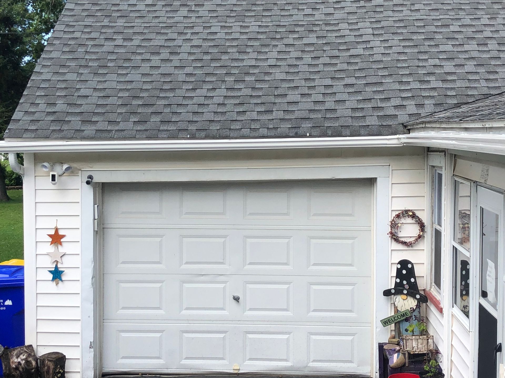 A picture of installed gutters on a white home, fixed up over a closed, white garage.