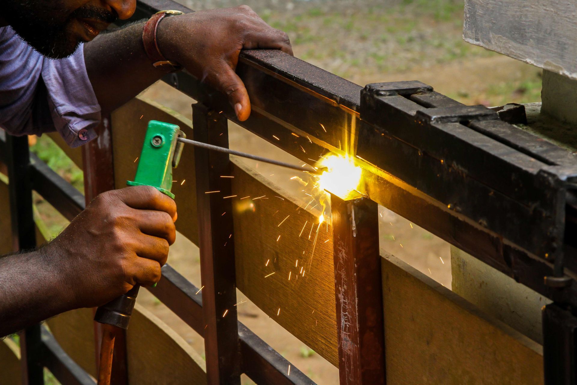 Person welding a metal frame, with bright sparks flying from the joint. Person welding a metal frame, with bright sparks flying from the joint.