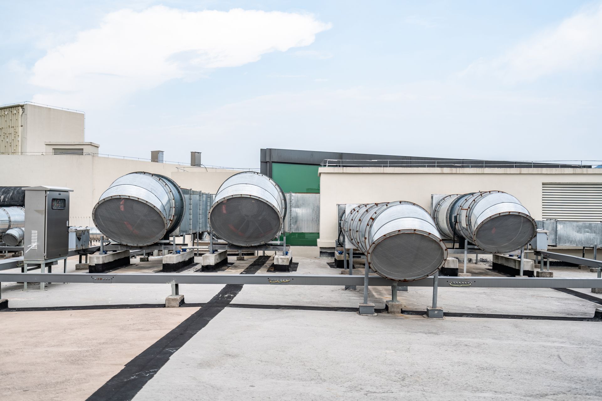 Row of air conditioning units on a rooftop, with white units against a blue sky.