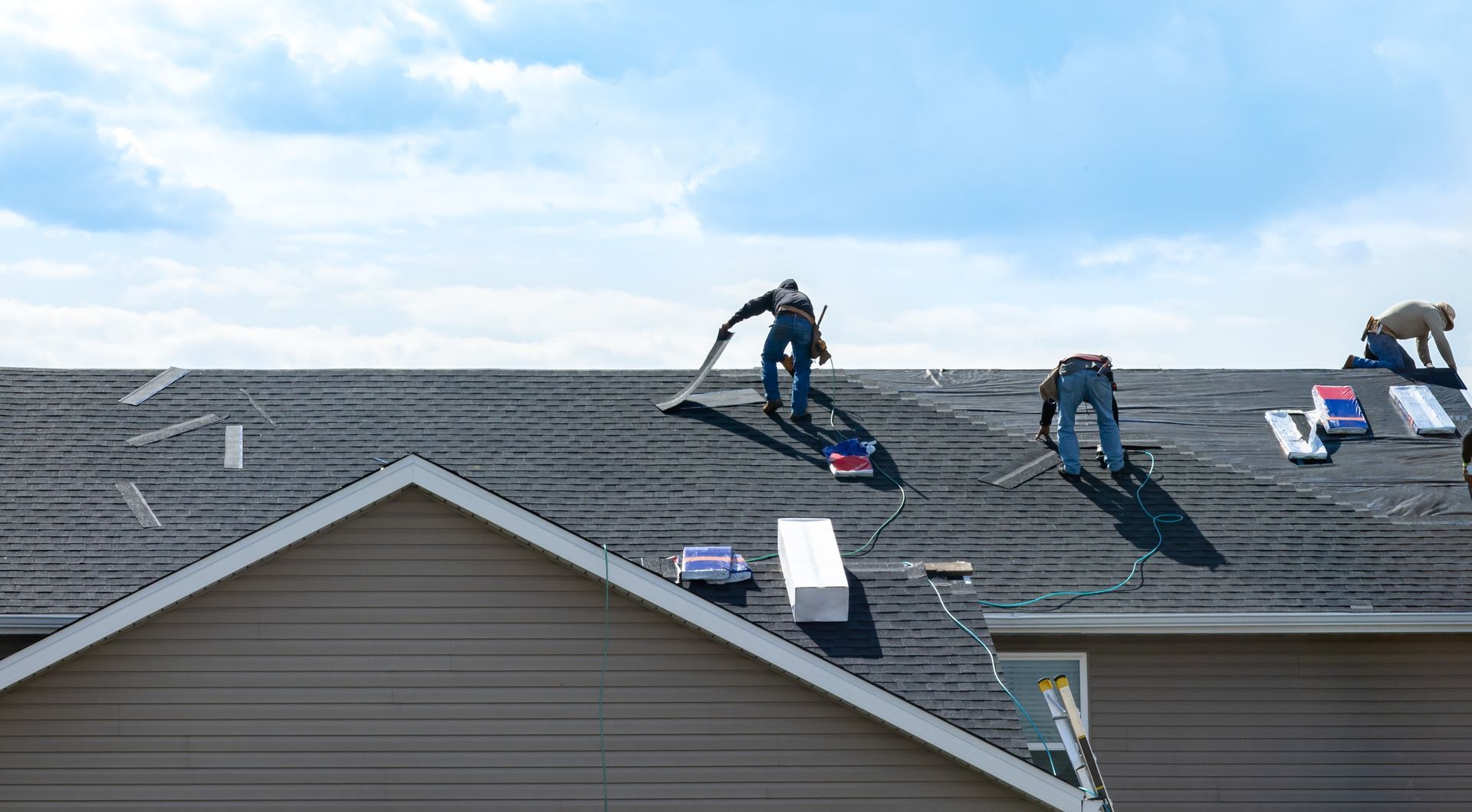 Workers installing solar panels on a residential roof under a cloudy sky