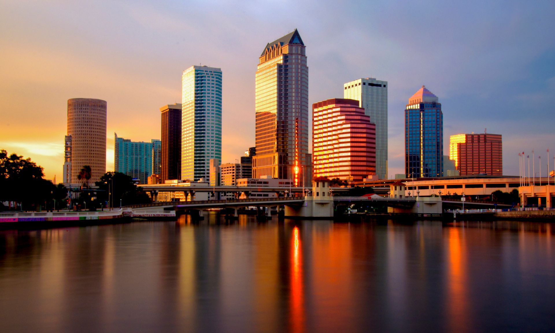 Skyline of Tampa, Florida, at sunset, with buildings reflecting warm light on the water.