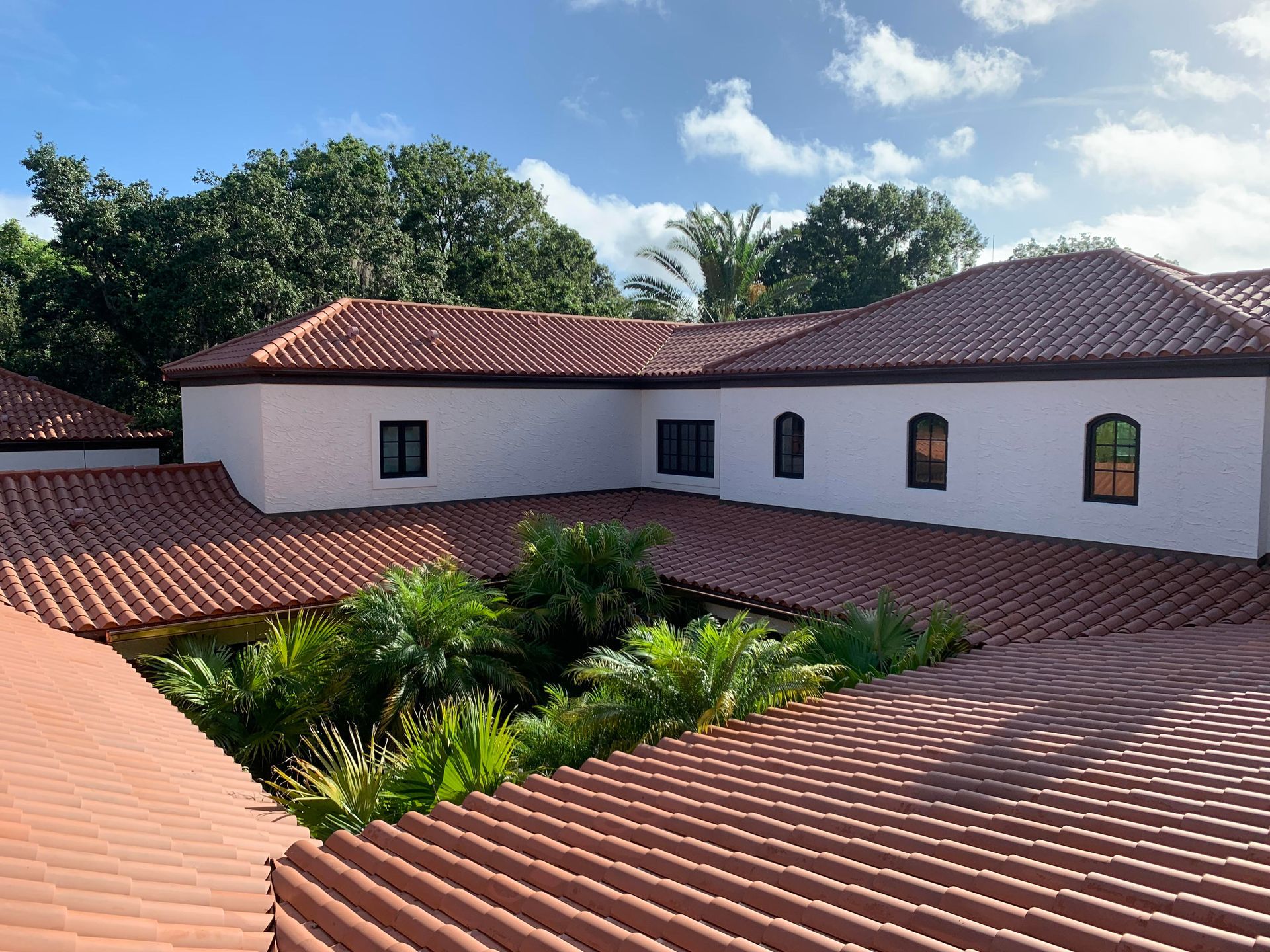 A coastal community with terracotta roofs and palm trees under a cloudy sky. A coastal community with terracotta roofs and palm trees under a cloudy sky.