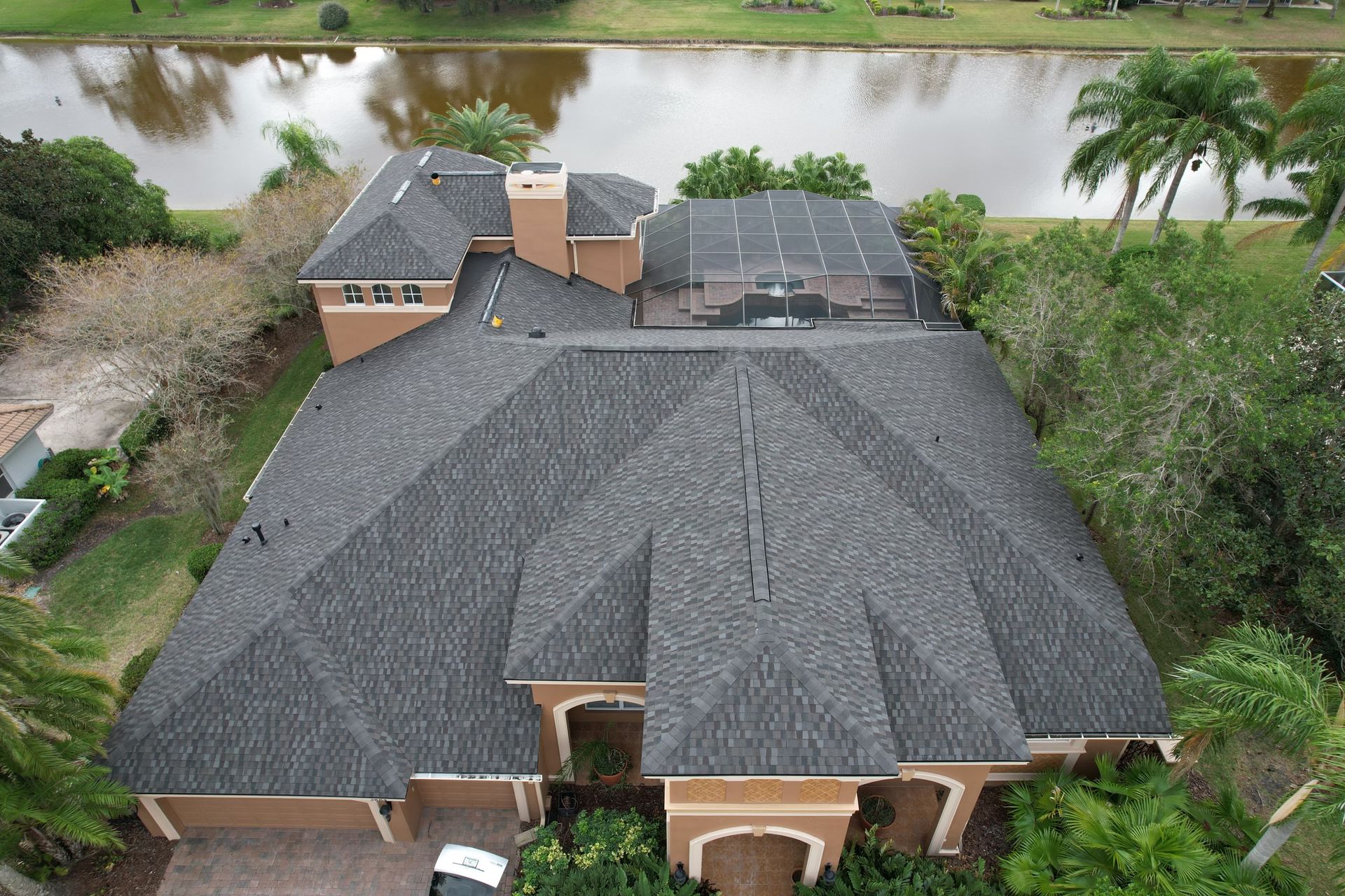 Two roofers in hard hats and safety vests installing tiles on a gray roof. Two roofers in hard hats and safety vests installing tiles on a gray roof.
