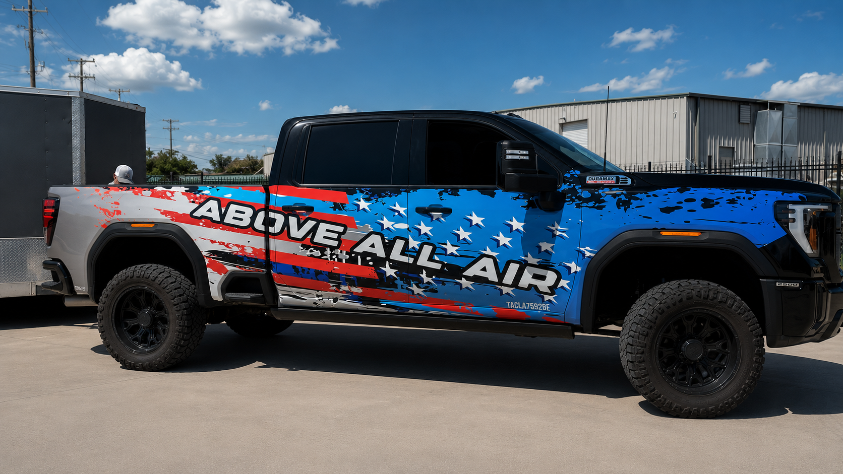 Blue-and-red off-road pickup with “REMOVE ALL AIR” graphics parked outdoors under a sunny sky