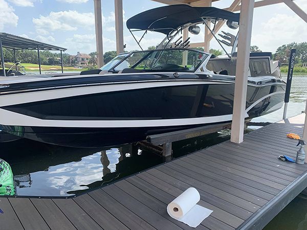 Black-and-white motor yacht docked beside a marina walkway with a canopy overhead
