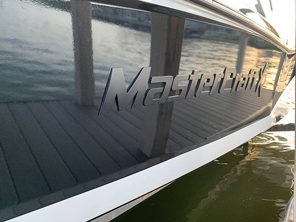 MasterCraft logo on a reflective boat hull beside the water