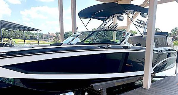 Black-and-white motorboat with a canopy docked at a covered marina slip