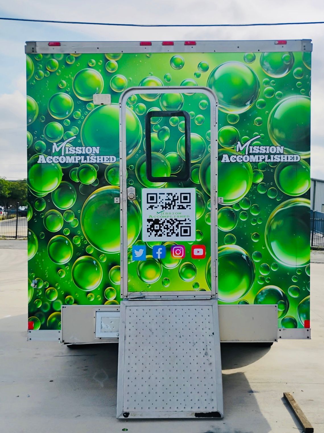 Green bubble-themed photo booth with QR code and social icons in an outdoor setting