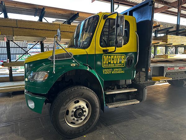 Green and yellow McCoy’s truck parked in a warehouse, side view with open cab door