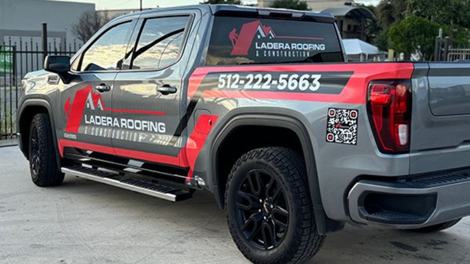 Gray and red LAURA ROOFING pickup truck with company logo and phone number parked outside
