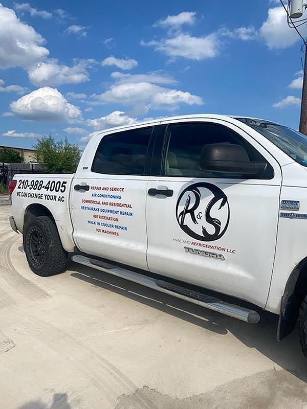 White work truck with company logos parked on a sunny street under a blue sky with clouds