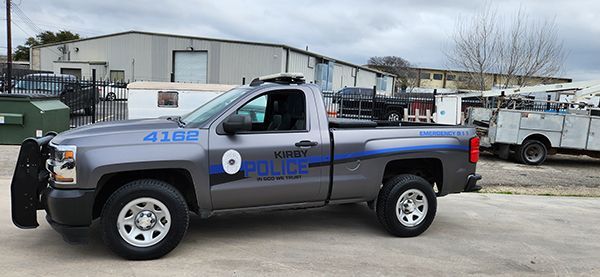 Blue police pickup truck parked in a lot, side view with police markings.