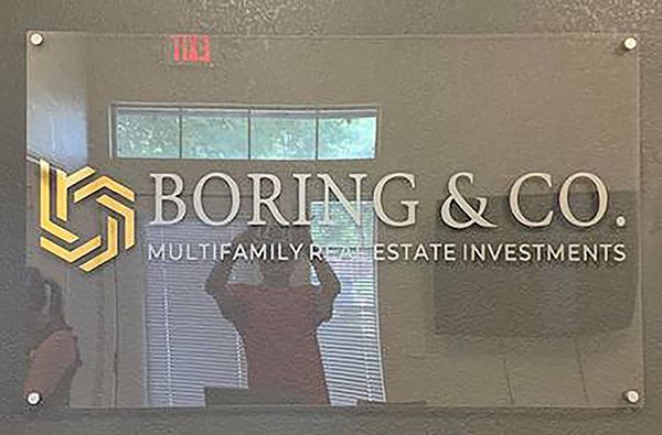 Boring & Co. sign on a glass wall, with gold logo and text for multifamily real estate investments