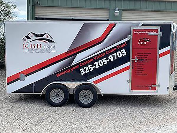 KBB trailer with red and black roof cleaning graphics and phone number parked on gravel by a garage