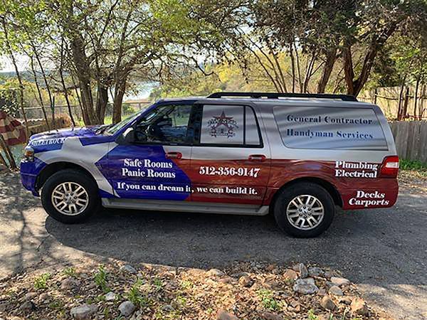 Branded SUV for a tree service parked on a rocky roadside under trees