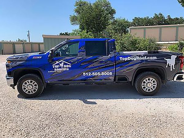 Blue TopDog Towing pickup truck parked on gravel lot under a sunny sky