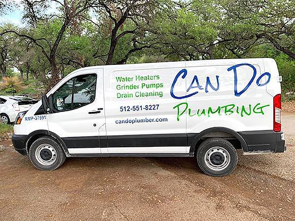White service van with “Can Do Plumbing” logo parked outdoors near trees.