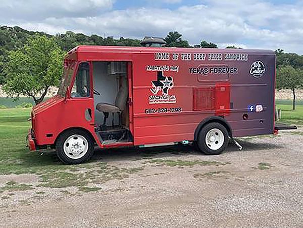 Red mobile food truck parked on a grassy roadside with Hindi text and a service window open