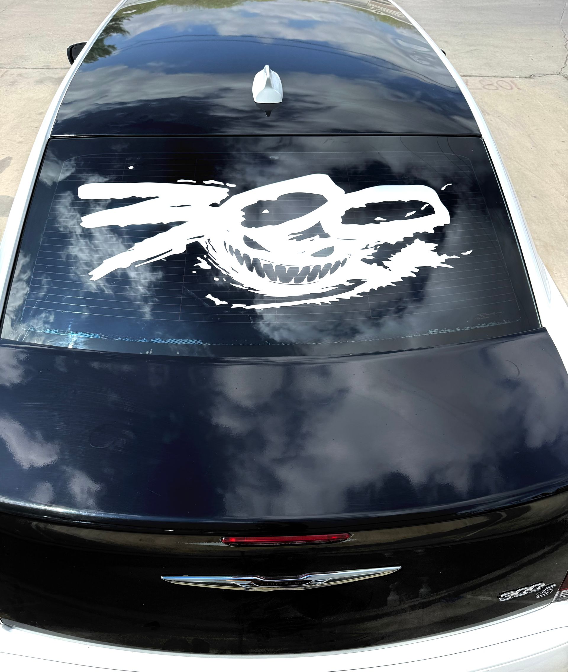 Black car rear window with a large white graffiti tag on the glass