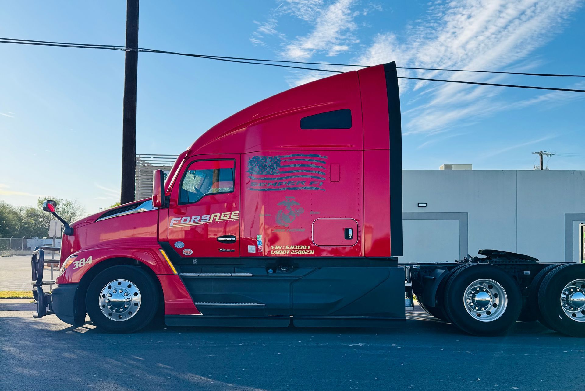 Bright red semi-truck cab on a road under a blue sky
