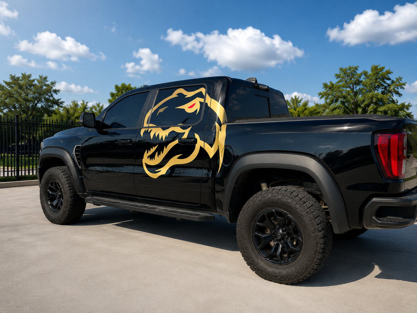 Black pickup truck with a gold tiger graphic parked on a street under a blue sky