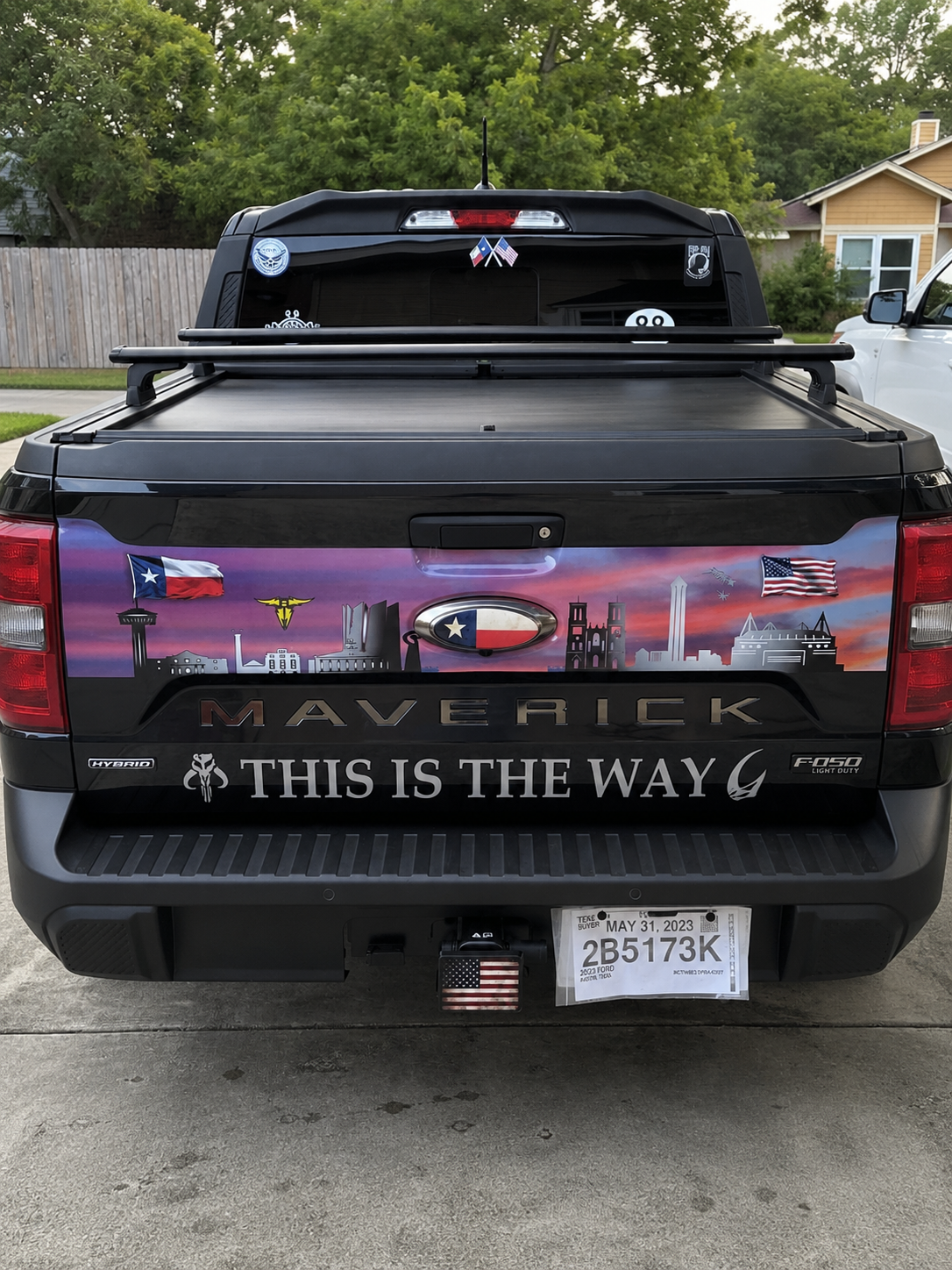 Black Ford Maverick pickup with “This is the Way” decals and a roof cargo box, parked in a driveway.