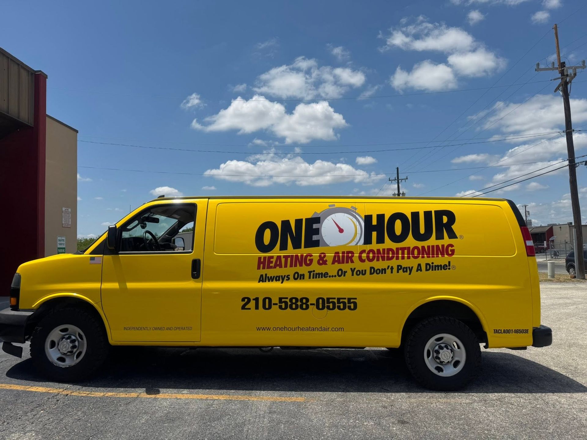 Yellow One Hour Heating & Air Conditioning van parked under a blue sky.