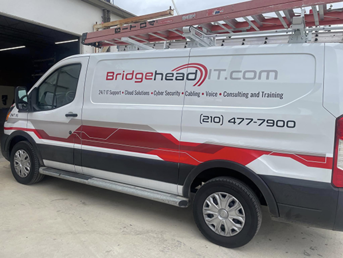 White BridgeheadIT.com service van parked outside, with red graphics and phone number 210-477-7900