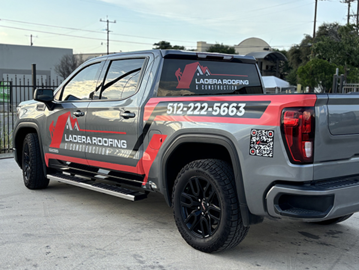 Red pickup truck with LADDER ROOFING branding and phone number parked outdoors.
