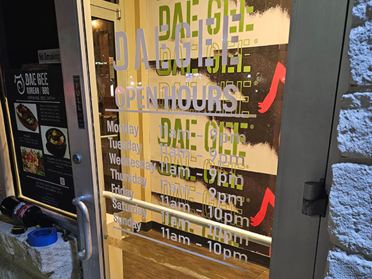 Restaurant door with opening hours and menu signs on glass storefront
