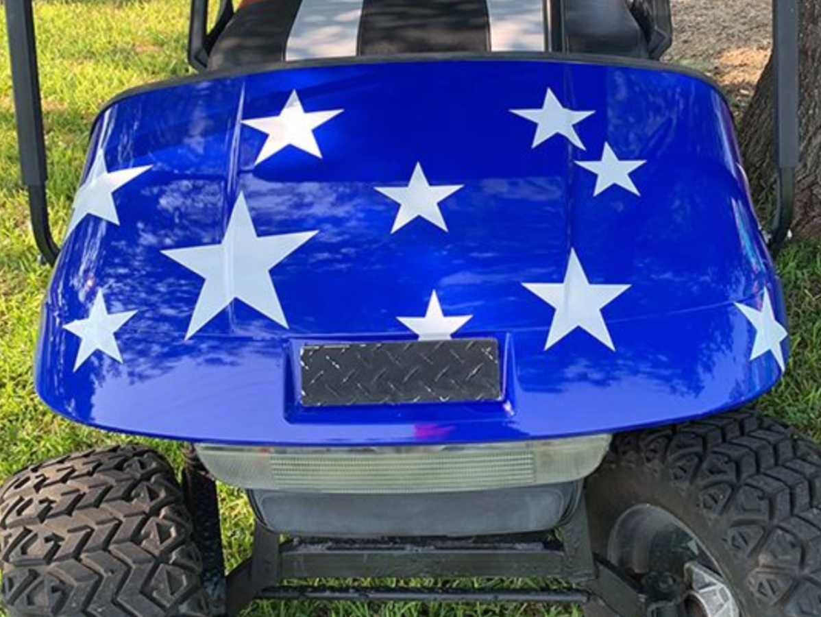 Blue golf cart decorated with white stars, viewed from the front outdoors.