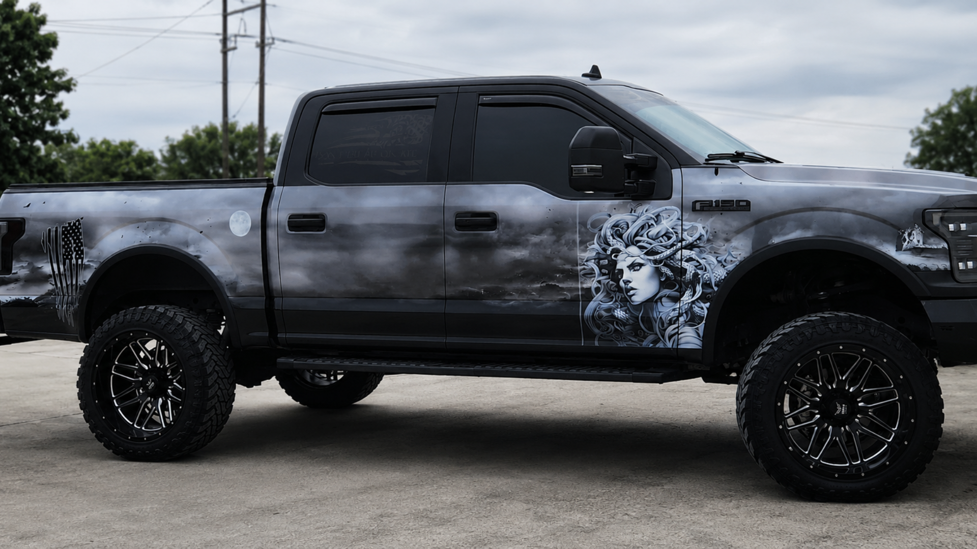 Black lifted pickup truck parked outdoors, with custom wolf graphic on the side.