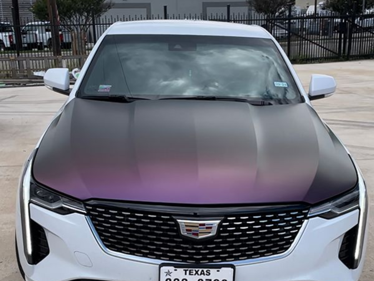 Front view of a white Cadillac SUV with a matte dark hood parked outdoors.