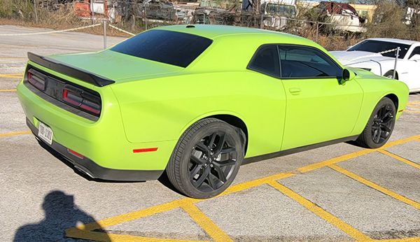 Bright lime-green sports car parked in a marked lot, viewed from the rear side.