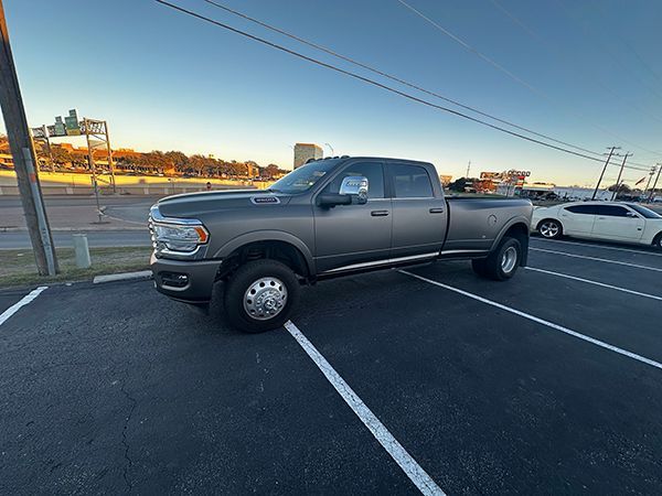 Gray pickup truck parked diagonally in a nearly empty parking lot at sunset
