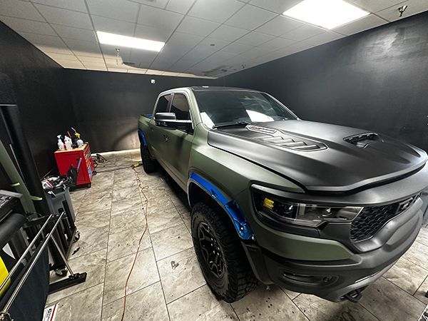 Black pickup truck in a detailing garage with tiled floor and cleaning supplies.