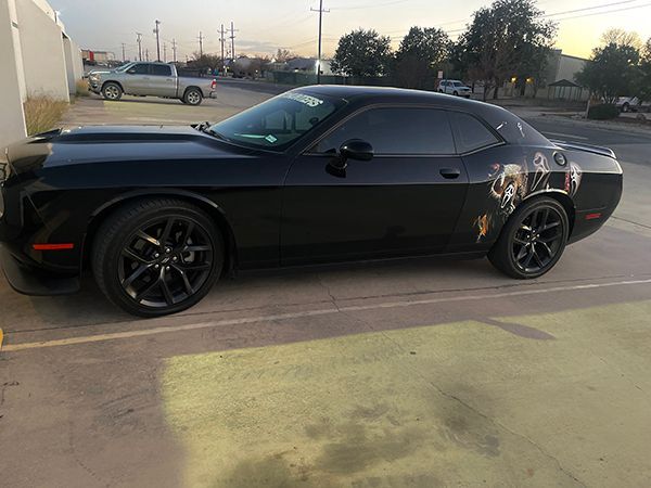 Black sports car parked in a lot at dusk, side view