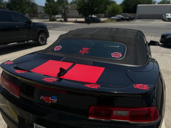 Black convertible with red racing decals parked in a lot, rear view