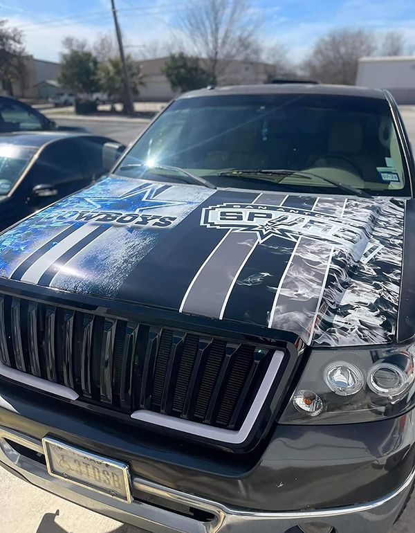 Black SUV with a custom patterned hood parked outdoors in a lot