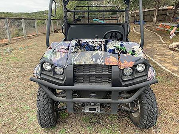 Camouflaged off-road utility vehicle parked outdoors under a shelter