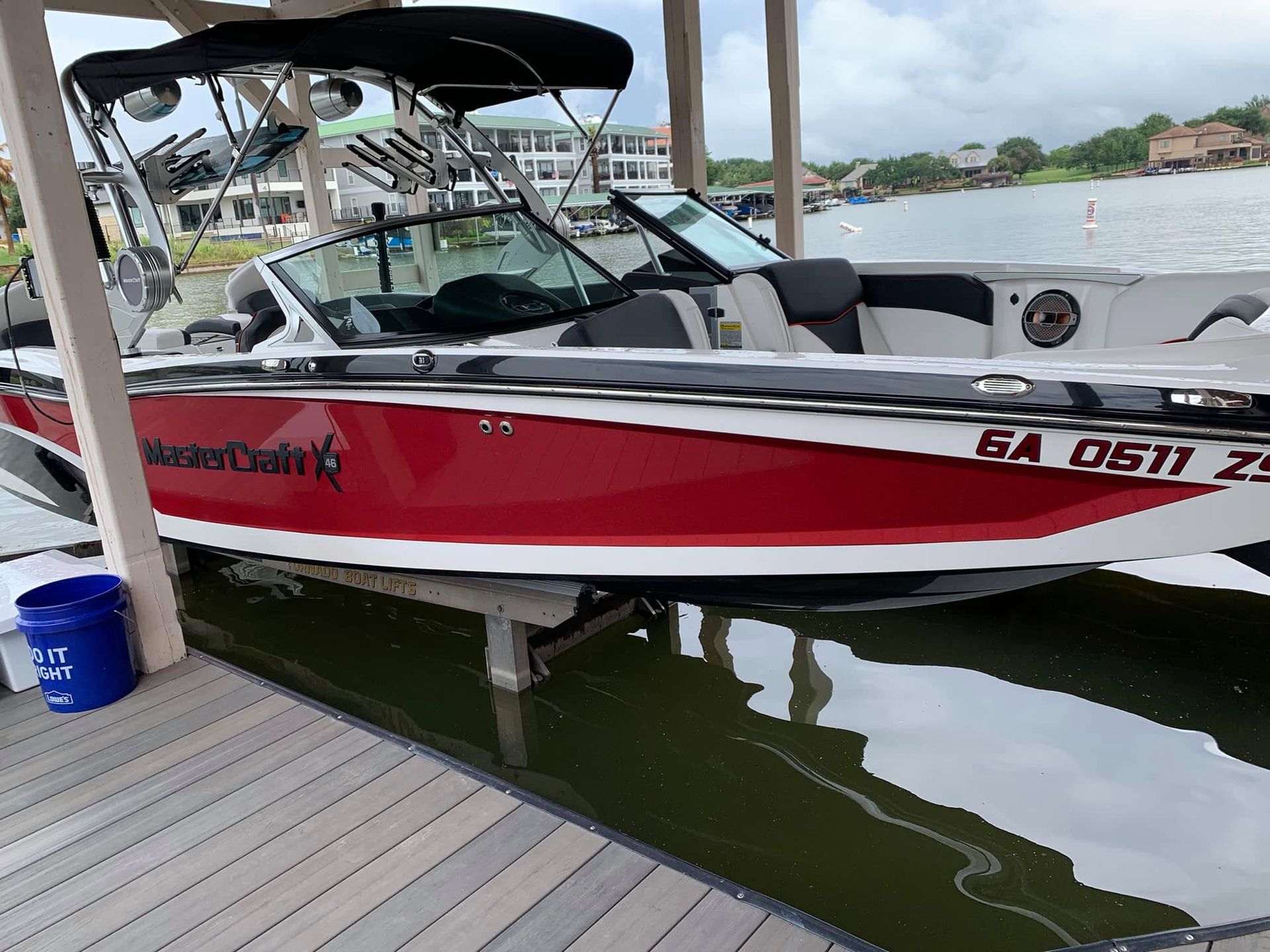 Red and white motorboat docked at a marina under a canopy, with calm water below.