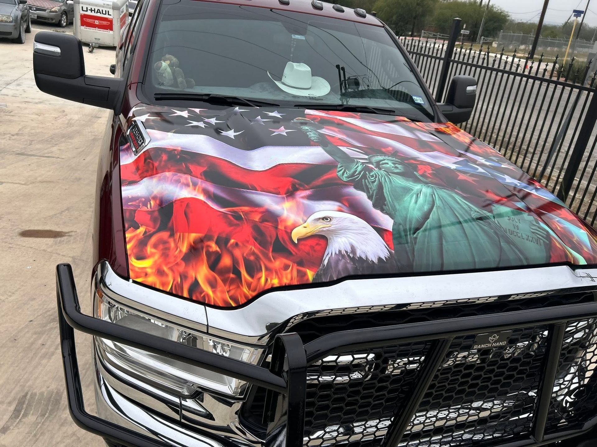 Pickup truck with a custom fiery hood wrap and black grille guard parked outdoors.